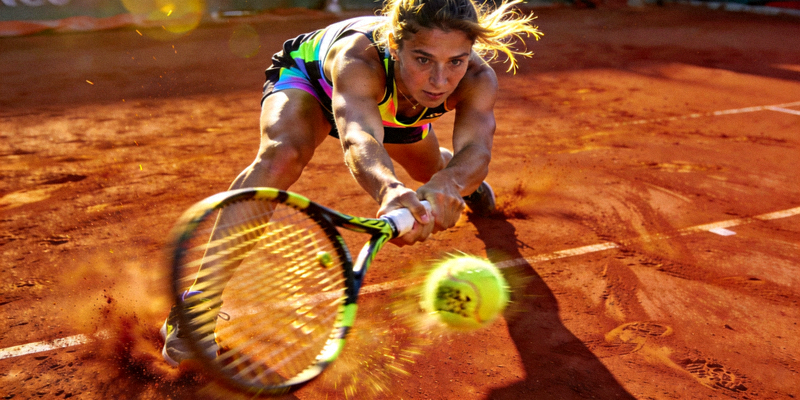 网球运动员在红土场上奋力击球的动作瞬间